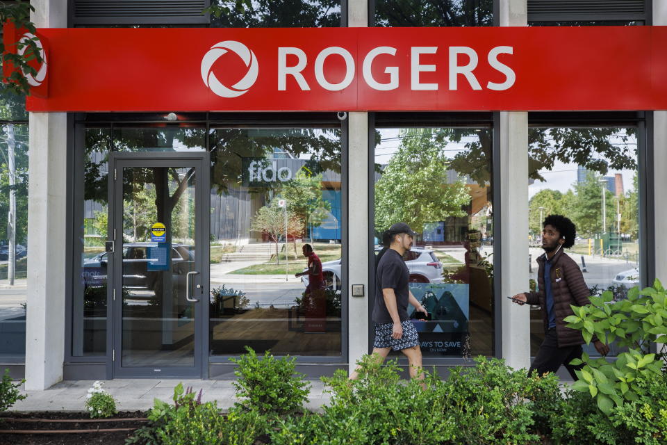 People walk past a Rogers wireless store in Toronto amid a country wide outage of the telecommunication company's services, Friday, July 8, 2022. (Cole Burston/The Canadian Press via AP)