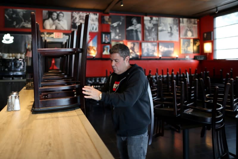 FILE PHOTO: Raul Gonzalez, Jr., 53 stacks chairs at his Mambos Cuban restaurant, which is being forced to close after 32 years, due to the global outbreak of the coronavirus disease (COVID-19), in Glendale