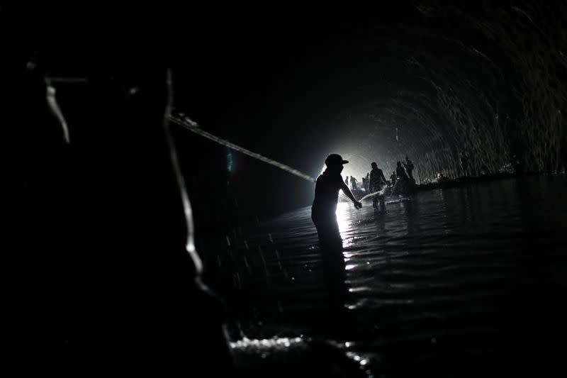 Men pull a rope inside a stalled tunnel construction project near El Avila mountain that borders the city of Caracas