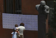 An Armenian woman reads voter lists at a polling station during a parliamentary election in Yerevan, Armenia, Sunday, June 20, 2021. Armenians are voting in a national election after months of tensions over last year's defeat in fighting against Azerbaijan over the separatist region of Nagorno-Karabakh. (AP Photo/Sergei Grits)