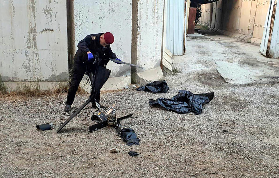 A security official inspects the wreckage of a drone at Baghdad airport, Iraq, Monday, Jan. 3, 2022. Two armed drones were shot down at the Baghdad airport on Monday, a U.S.-led coalition official said, an attack that coincides with the anniversary of the 2020 U.S. killing of a top Iranian general. (International Coalition via AP)