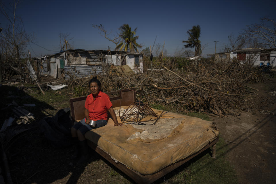 Mari Carmen Zambrano poses for a photo on her broken and wet bed as she dries it outside her home that lost its roof to Hurricane Ian in La Coloma, in the province of Pinar del Rio, Cuba, Wednesday, Oct. 5, 2022. (AP Photo/Ramon Espinosa)