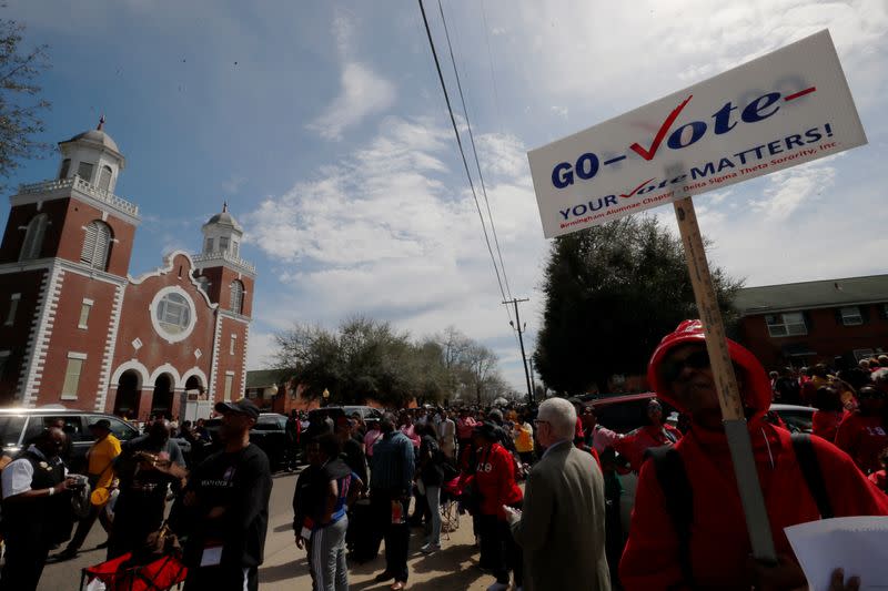 A woman carries a sign reading "Go Vote" in Selma