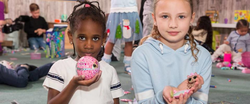 Two girls holding L.O.L Surprise Pets toys