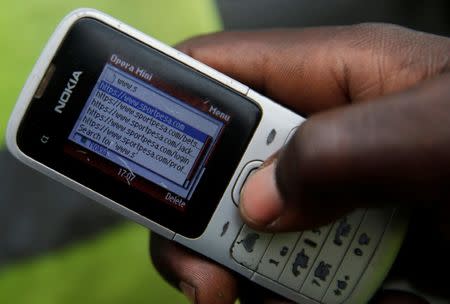 A gambler uses his cell phone to launch the Sportpesa online betting link, along the streets of Nairobi, Kenya, January 3, 2018. REUTERS/Thomas Mukoya