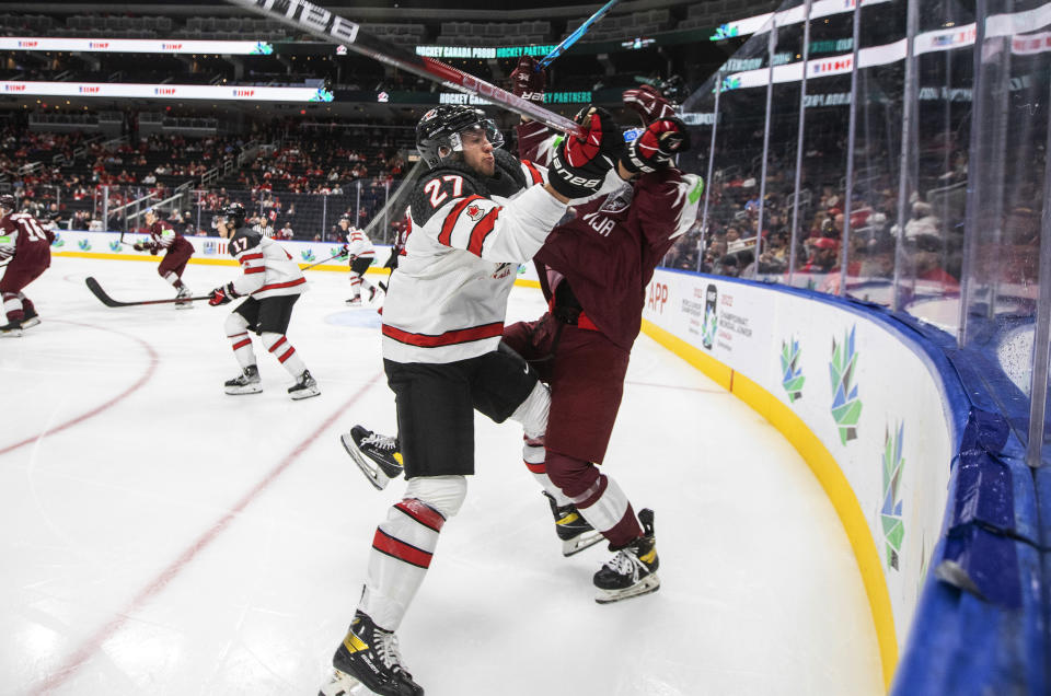 Canada's Will Cuylle (27) checks Latvia's Niks Fenenko (4) during the second period of an IIHF junior world hockey championships game Wednesday, Aug. 10, 2022, in Edmonton, Alberta. (Jason Franson/The Canadian Press)