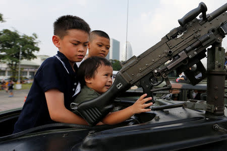 Children play with a weapon on op of an army vehicle during Children's Day celebration at a military facility in Bangkok, Thailand January 14, 2017. REUTERS/Jorge Silva