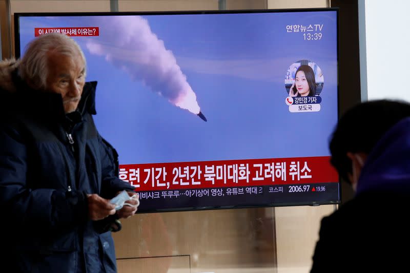 A man walks past a TV showing a file picture for a news report on North Korea firing two unidentified projectiles, in Seoul