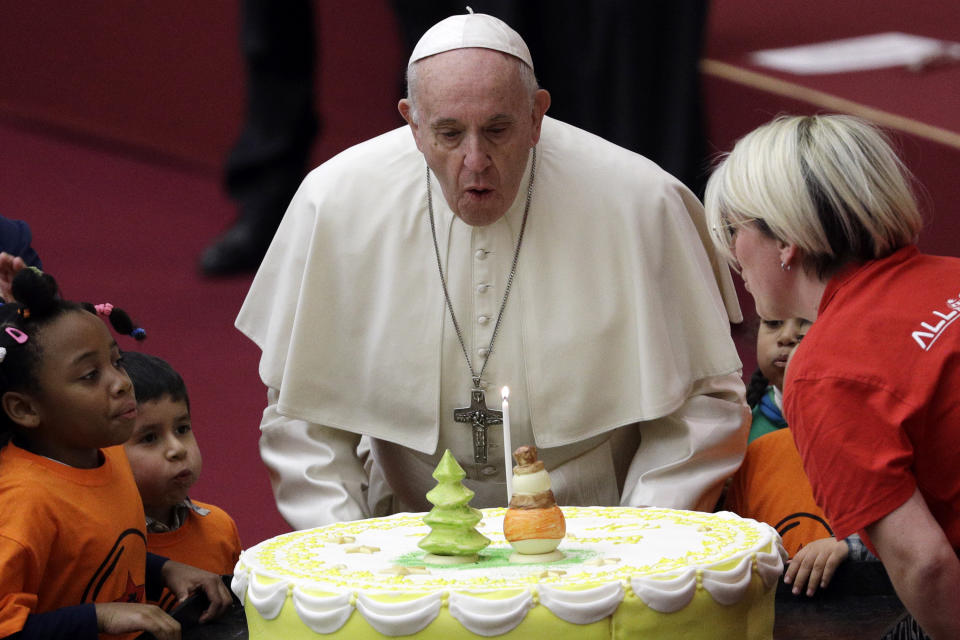 Pope Francis blows a candle atop of a cake he was offered on the eve of his 82nd birthday during audience with children and family from the dispensary of Santa Marta, a Vatican charity that offers special help to mothers and children in need, in the Paul VI hall at the Vatican, Sunday, Dec. 16, 2018. (AP Photo/Gregorio Borgia)