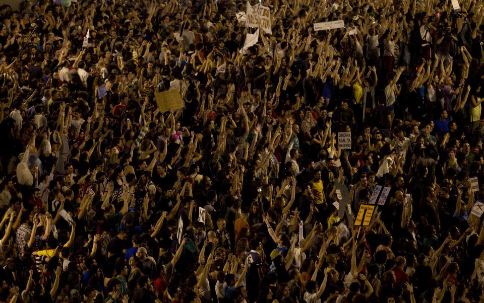 Protesters raise their hands during a protest in the Puerta del Sol plaza in central Madrid Saturday May 12, 2012. The protesters returned to Sol to mark the anniversary of the protest movement that inspired groups in other countries. The protests began May 15 last year and drew hundreds and thousands of people calling themselves the indignant movement. The demonstrations spread across Spain and Europe as anti-austerity sentiment grew. (AP Photo/Paul White)