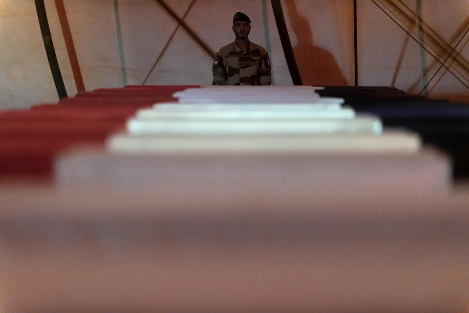 In this Wednesday, Nov. 27, 2019, photo provided by French Defense Communication and Audiovisual Department (ECPAD), a soldier stands guard by the coffins of the 13 French soldiers, in Gao, Mali. France’s Defense Minister Florence Parly arrived in northern Mali on Wednesday after a helicopter collision killed 13 French soldiers fighting Islamic State group-linked extremists, while some in the West African country debated France’s military presence. (Thomas Peudeleux/ECPAD via AP)