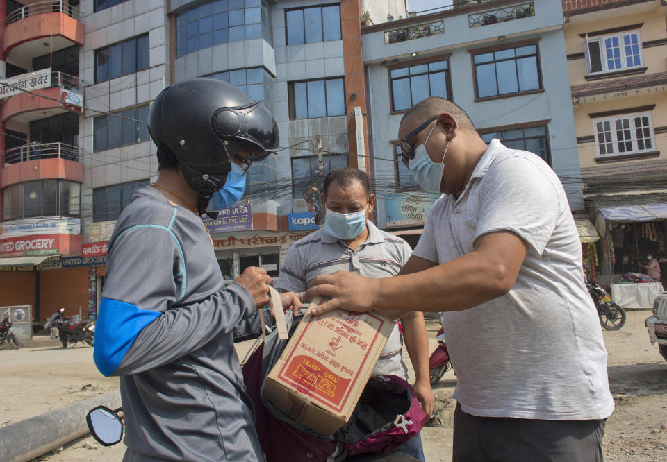 Trekking guide Ang Phurba Sherpa, center, distributes ration to fellow guides, in Kathmandu, Nepal, Monday, June 7, 2021. Most Sherpa guides in Nepal famed for the climbing skills have had little or no work guiding foreign trekkers on Nepal's mountains because of the pandemic but trekking guide Ang Phurba Sherpa is spending his savings to help fellow guides and workers who are struggling for their livelihood. (AP Photos/Bikram Rai)