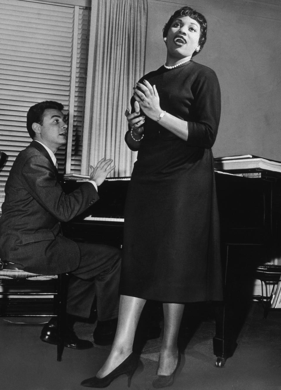 <p>1955 – LEONTYNE PRICE – ENTERTAINMENT – First African-American woman to appear in a telecast opera, (NBC’s production of ‘Tosca’). — Arnold Gamson, conductor of the American Opera Society, plays the piano as he coaches American soprano Leontyne Price for ‘Julius Caesar’ on September 28, 1956. (Robert Walker/New York Times Co./Getty Images) </p>