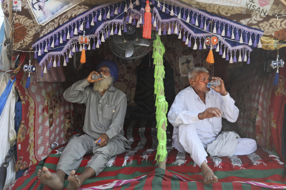 Indian farmers drink water sitting at the back of their tractor trolly as they camp at Singhu, along the Delhi-Haryana border, Friday, March 5, 2021. Saturday marks 100 days of the ongoing farmer protests against the contentious new agricultural reform laws which have led tens of thousands of farmers to blockade key highways leading to the capital. Multiple rounds of talks have failed to produce any breakthrough on the farmers' key demand to revoke the legislation. (AP Photo/Manish Swarup)