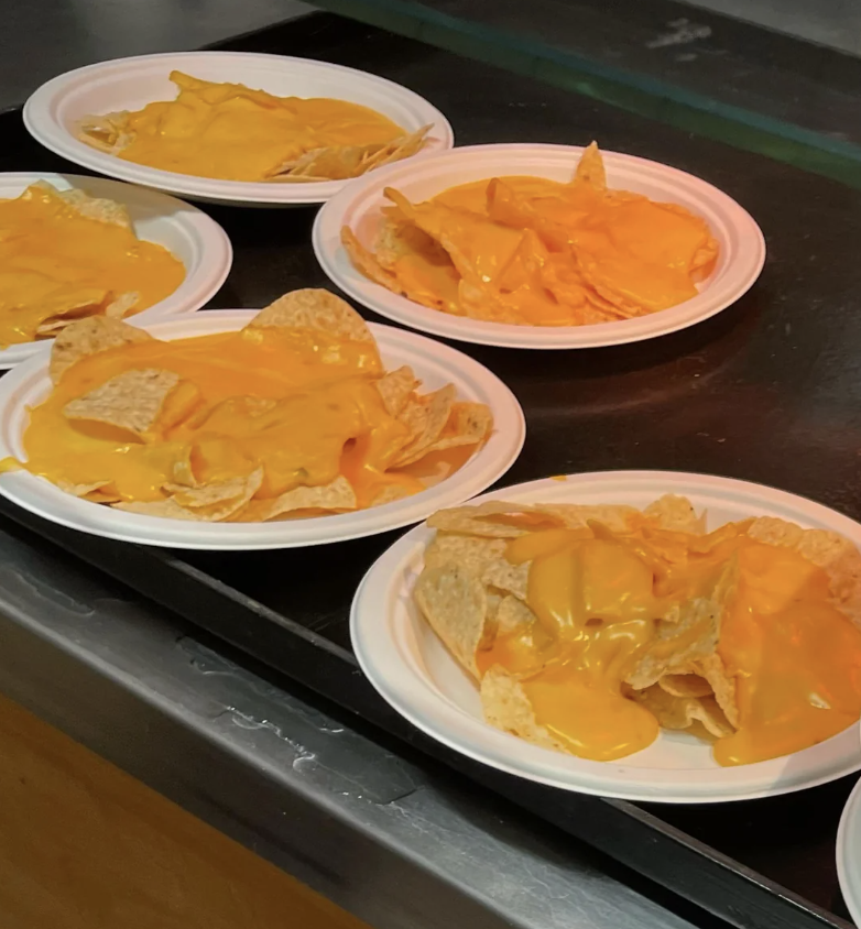 Several plates of nachos with a generous amount of cheese sauce