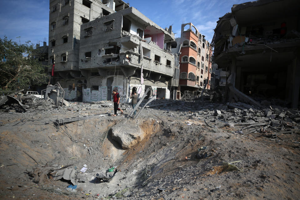 Two people look at damaged multistory buildings following overnight Israeli airstrikes in Gaza City.