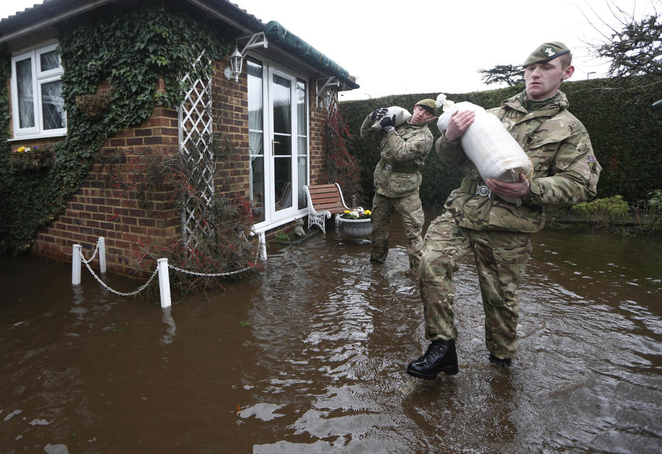 British army soldiers carry sandbags at the entrance to a flooded house at Chertsey, England, Wednesday, Feb. 12, 2014. The River Thames has burst its banks after reaching its highest level for many years, flooding riverside towns upstream of London, including Chertsey which is about 30 miles west of central London. Some hundreds of troops have been deployed to assist with flood protection and to get medical assistance to the sick and vulnerable.(AP Photo/Sang Tan)