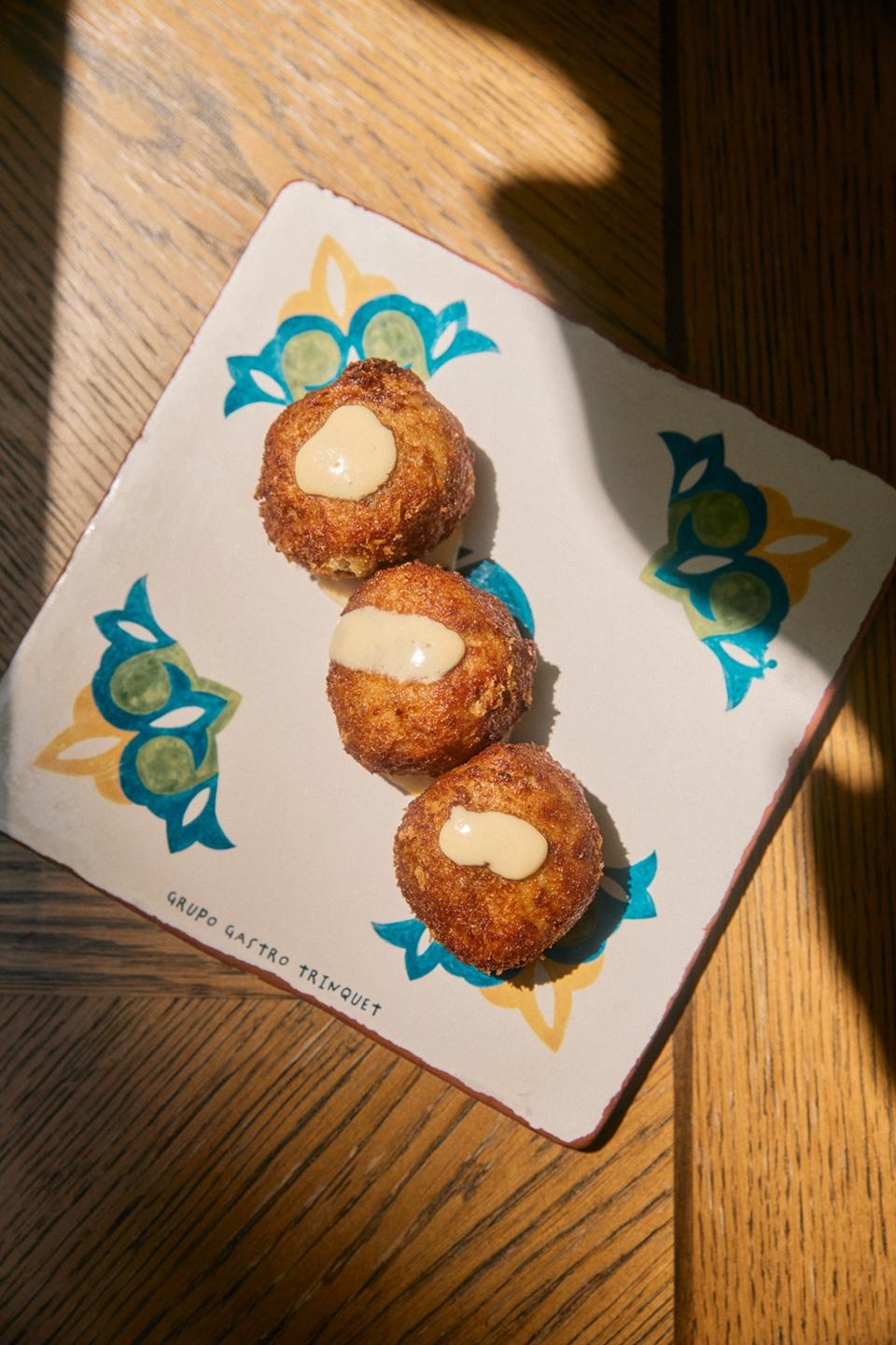 Three croquetas served on a plate with floral detailing