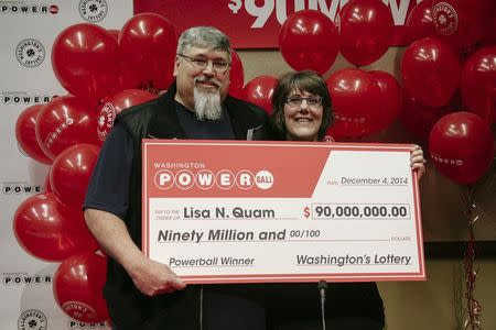 Lisa Quam and her husband Everett hold a check for $90 million during a news conference in Olympia, Washington December 4, 2014 in this handout picture provided by the Washington State lottery. REUTERS/Washington State Lottery/Handout