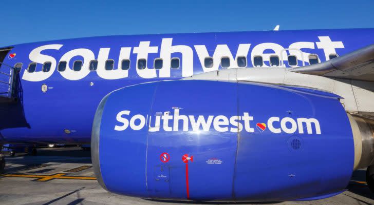 An image of the side of a blue Southwest plane with a blue sky in the background.
