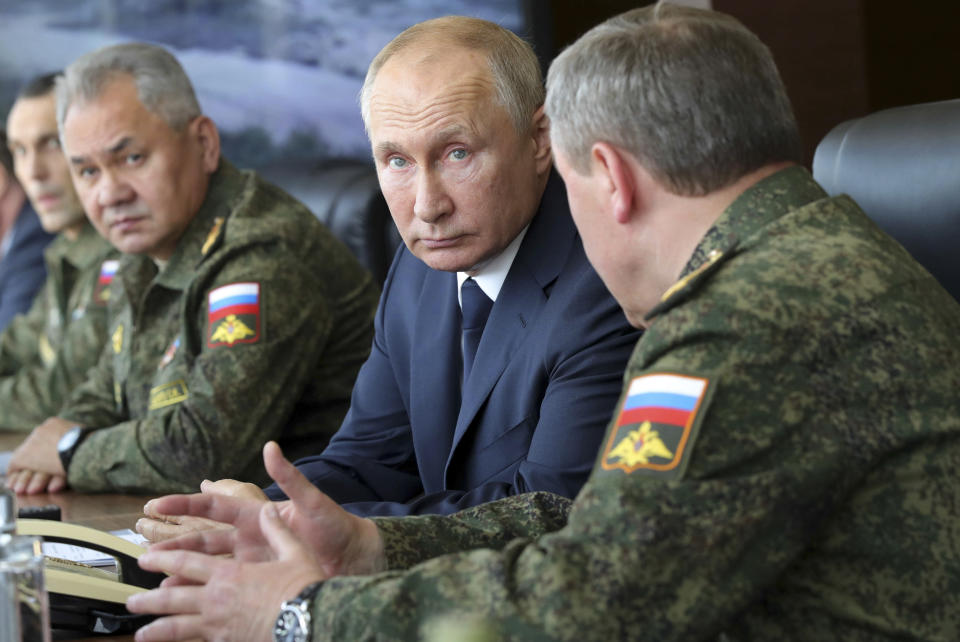 FILE - Russian President Vladimir Putin, center, and Russian Defense Minister Sergei Shoigu, left, attend the main stage of the Kavkaz-2020 strategic command-and-staff exercises at the Kapustin Yar training ground, Russia, Sept. 25, 2020. Amid a Russian troop buildup near Ukraine that raised Western fears of an invasion, Putin has urged the West to persuade Ukrainian authorities to comply with the terms of a 2015 peace deal for eastern Ukraine. (Mikhail Klimentyev, Sputnik, Kremlin Pool Photo via AP, File)