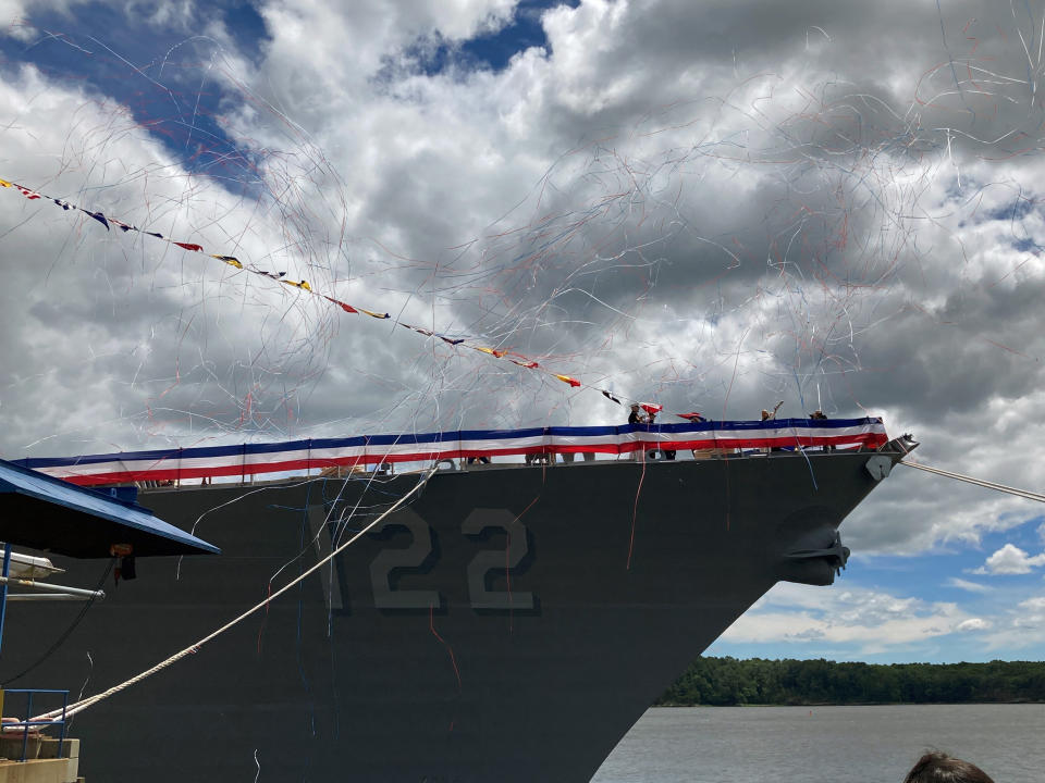 Co-sponsor Ryan Manion salutes a crowd after christening the future USS Basilone by crashing a bottle of sparkling wine on the bow of the Navy destroyer on Saturday, June 18, at Bath Iron Works in Bath, Maine. The christening of a Navy destroyer on Saturday highlighted the sacrifices of two generations — the ship’s namesake killed in World War II and another Marine who died more than 60 years later. The future USS Basilone bears the name of a Marine who was awarded the Medal of Honor before his death on Iwo Jima. (AP Photo/David Sharp)