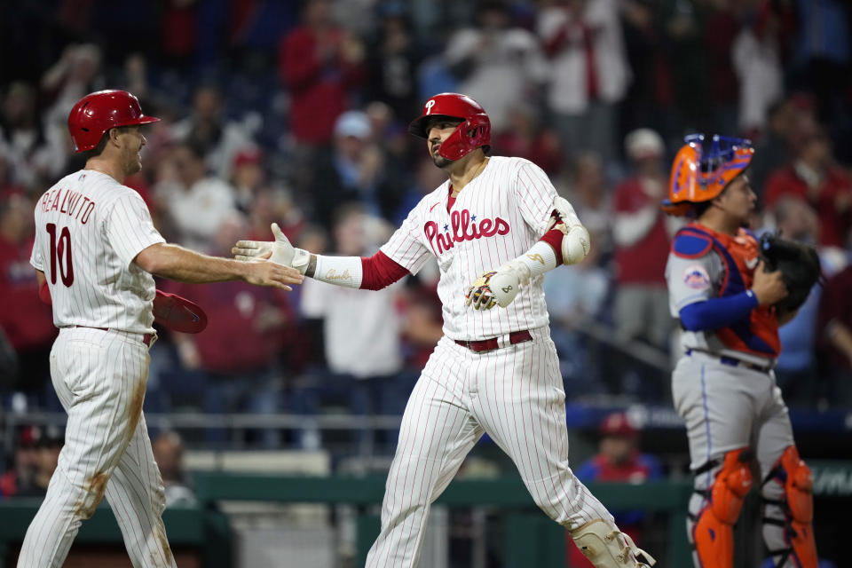 Philadelphia Phillies' Nick Castellanos, center, and J.T. Realmuto, left, celebrate past New York Mets catcher Francisco Alvarez after Castellanos' two-run home run during the fourth inning of a baseball game, Sunday, Sept. 24, 2023, in Philadelphia. (AP Photo/Matt Slocum)