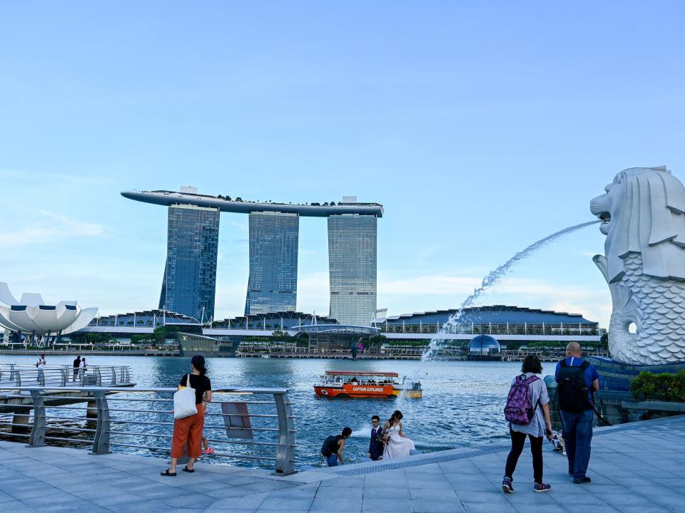 People walk along the promenade overlooking the Marina Bay Sands hotel and resort in Singapore.