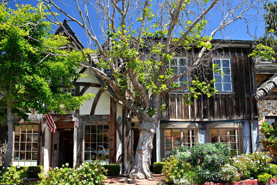 View of an old wooden building with glass windows, urban trees and an American flag in the center of Carmel, California.