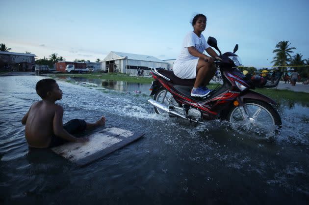 A woman rides her scooter through floodwaters occurring around high tide in a low-lying area near the airport in 2019 in Funafuti, Tuvalu. The South Pacific island nation of about 11,000 people has been classified as 