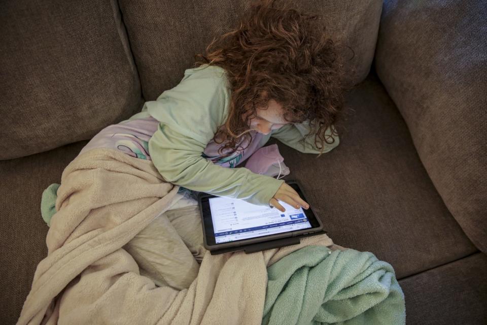 Lounging on the couch, Madelynn Singer uses her tablet at home in Porter Ranch.