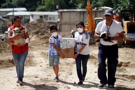 Residents carry their belongings and pets, as they voluntarily evacuate from an area affected by a mudslide in Santa Catarina Pinula, on the outskirts of Guatemala City, October 11, 2015. REUTERS/Josue Decavele