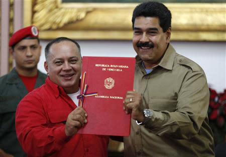 Venezuelan President Nicolas Maduro (R) receives from National Assembly President Diosdado Cabello a document approving a law which grants him with decree powers in Caracas, November 19, 2013. REUTERS/Carlos Garcia Rawlins