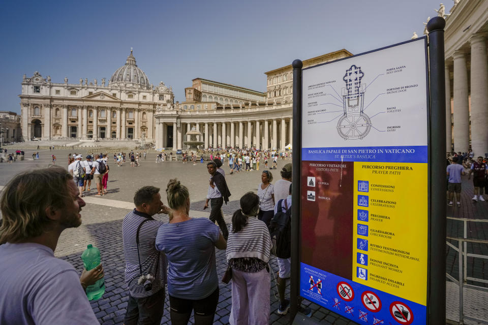 A man reads a sign explaining how to enter St. Peter's Basilica for praying or for a touristic visit at The Vatican, Wednesday, July 12, 2023. With tourism reaching or surpassing pre-pandemic levels across Southern Europe this summer, iconic sacred sites struggle to find ways to accommodate both the faithful who come to pray and millions of increasingly secular visitors attracted by art and architecture. (AP Photo/Alessandra Tarantino)