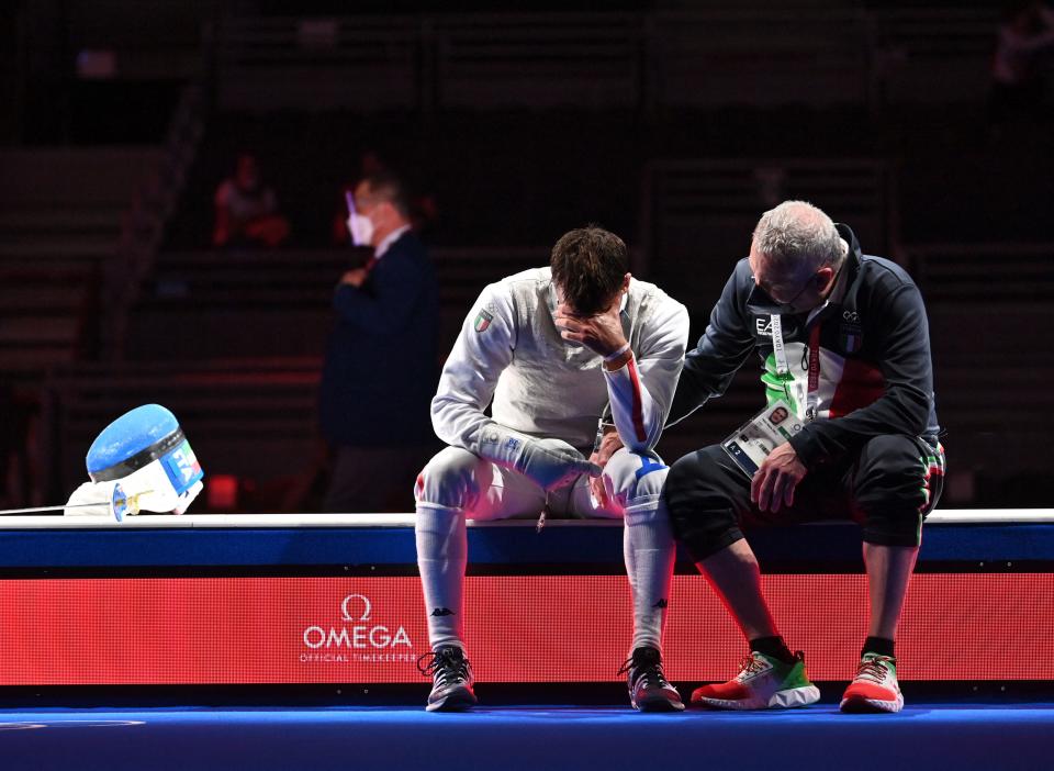 <p>Italy's Daniele Garozzo (L) is consolate by his coach Fabio Maria Galli after loosing against Hong Kong's Cheung Ka Long in the mens individual foil gold medal bout during the Tokyo 2020 Olympic Games at the Makuhari Messe Hall in Chiba City, Chiba Prefecture, Japan, on July 26, 2021. (Photo by Fabrice COFFRINI / AFP) (Photo by FABRICE COFFRINI/AFP via Getty Images)</p> 