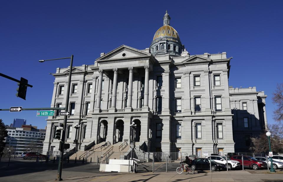 A cyclist passes by Colorado's State Capitol building in Denver.