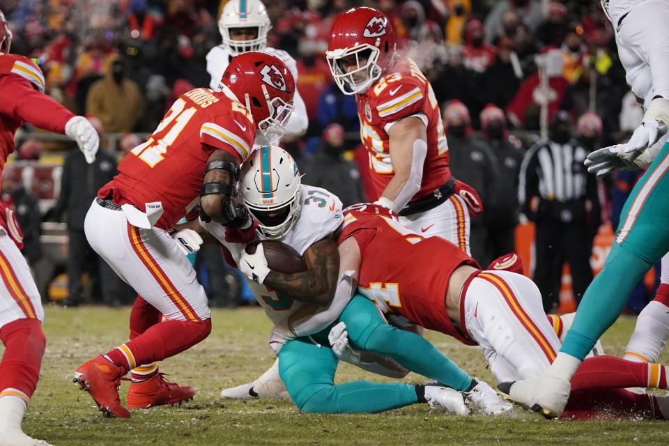 Jan 13, 2024; Kansas City, Missouri, USA; Miami Dolphins running back Raheem Mostert (31) is brought down by Kansas City Chiefs safety Mike Edwards (21) and linebacker Drue Tranquill (23) during the first half of the 2024 AFC wild card game at GEHA Field at Arrowhead Stadium. Mandatory Credit: Denny Medley-USA TODAY Sports