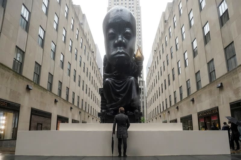 A man stands and looks at Sanford Biggers statue 'Oracle' in New York City