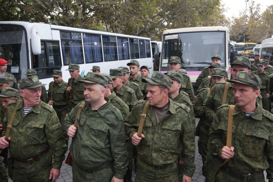 Men in army uniforms stand in lines.