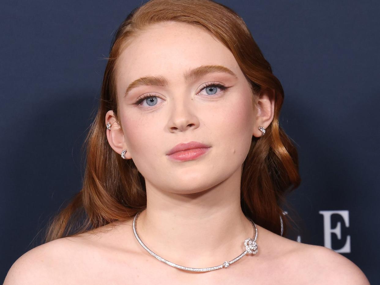 Sadie Sink poses for photos on the red carpet in a black strapless gown.