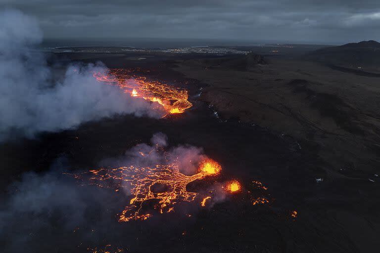  Así se ve el flujo brillante de magma y la humareda del volcán