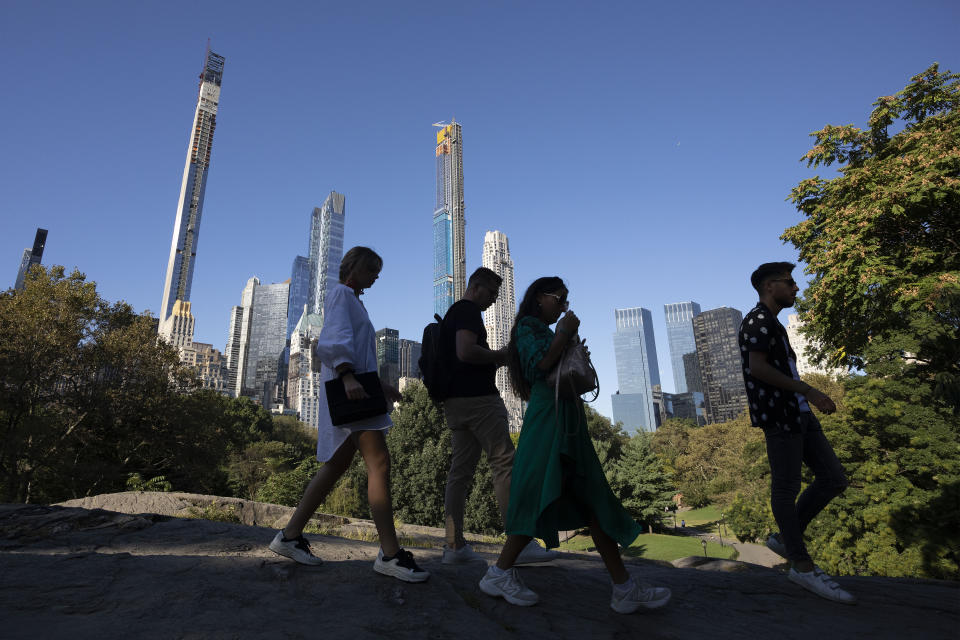 People hike through New York's Central Park with the Central Park Tower, center, behind them, Tuesday, Sept. 17, 2019. At 1550 feet (472 meters) the tower is the world's tallest residential apartment building, according to the developer, Extell Development Co. (AP Photo/Mark Lennihan)