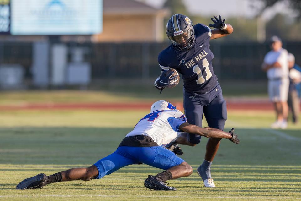 Heritage Hall's Rashaud Smith (11) escapes a tackle by Millwood's Terrance Taffee (14) during a high school football game at Heritage Hall in Oklahoma City on Friday, Aug. 31, 2023.