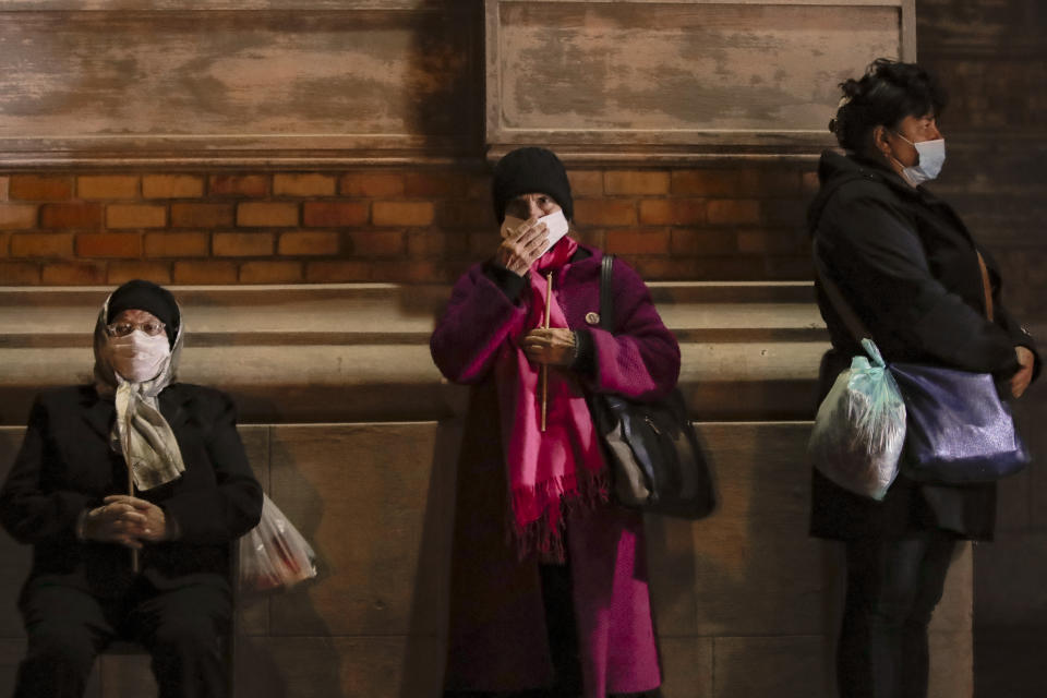 Orthodox worshipers, wearing masks for protection against the COVID-19 infections, wait for a religious service in the Black Sea port of Constanta, Romania, late Tuesday, May 26, 2020. (AP Photo/Vadim Ghirda)