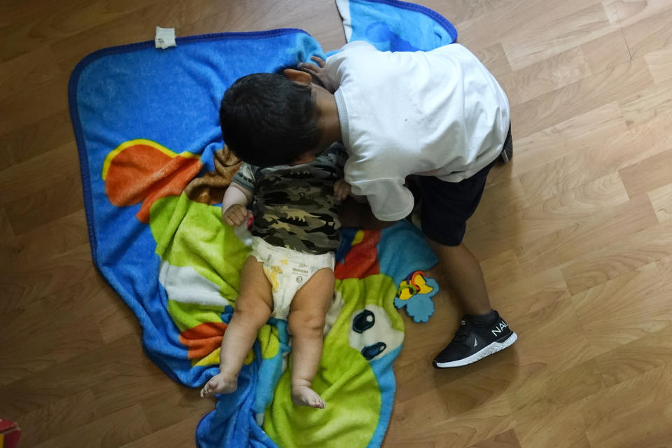 Alexander, 3, who is being treated for developmental delays, give his infant brother some affection at the family's West Chicago, Ill., home Tuesday, Aug. 8, 2023. Alexander qualified for five Early Intervention therapies in summer 2021, physical, occupational, developmental, behavioral and speech when he was about a year old. But the family waited more than a year to get any of these services in-person. (AP Photo/Charles Rex Arbogast)