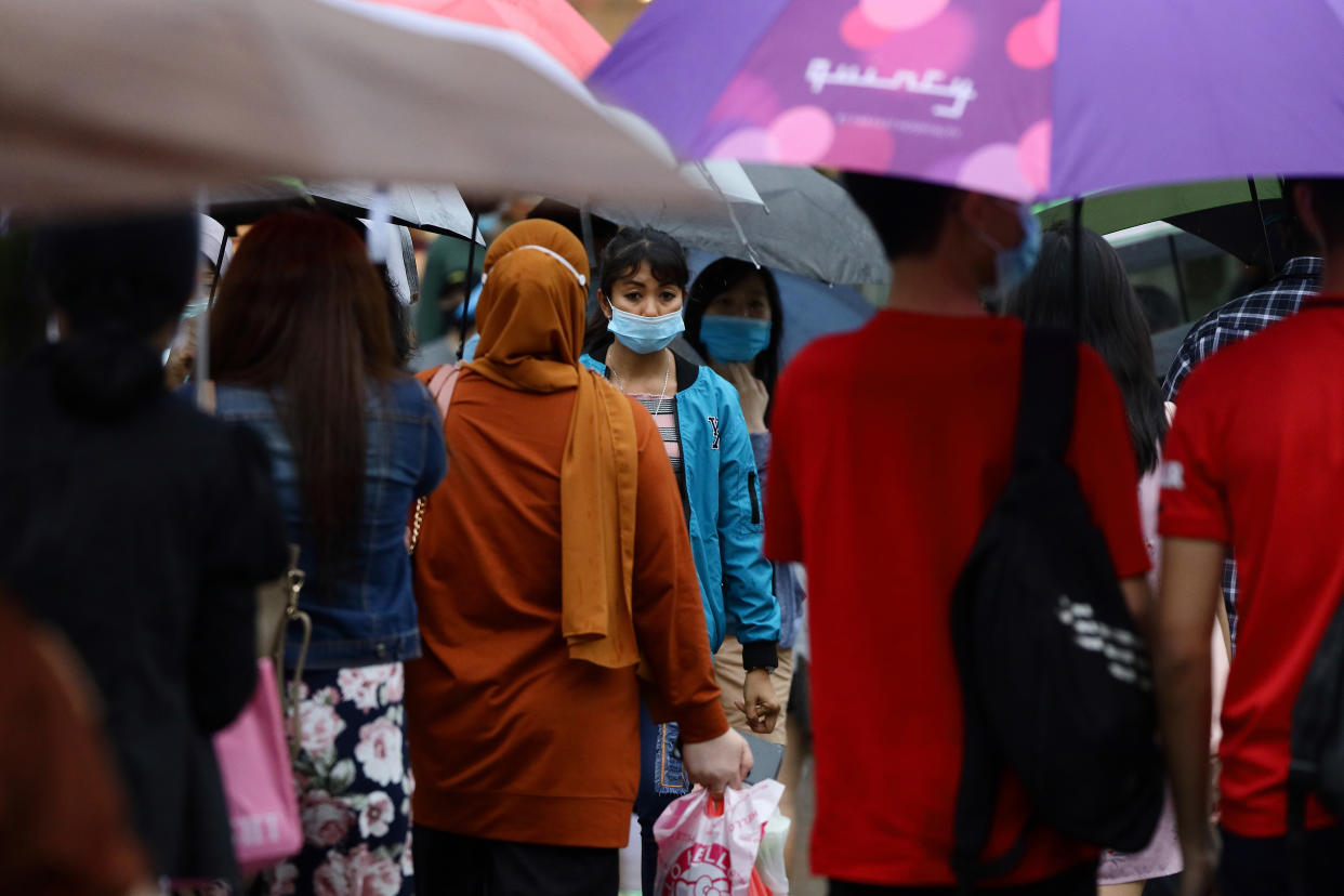 People wearing protective masks cross a street in the rain in Singapore. 