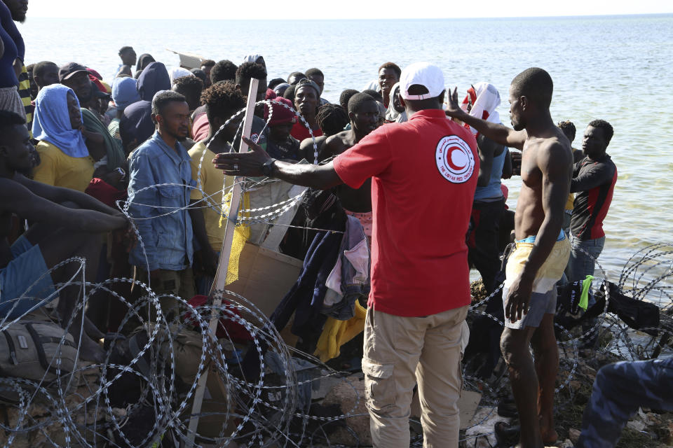 FILE - Migrants gather near the Libyan-Tunisia border, as Libyan security forces and Libyan Red Cross workers distribute food aid to them on Sunday, July 23, 2023. Tunisian authorities have so far skirted a direct response to accusations by human rights organizations, Libyan authorities and accounts by migrants themselves that they have conducted mass expulsions across their borders, which is forbidden under international law. (AP Photo/Yousef Murad, File)