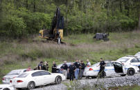 <p>Police gather on a road next to construction equipment in a wooded area near where Waffle House shooting suspect Travis Reinking was captured, Monday, April 23, 2018, in Nashville, Tenn. Police say Reinking shot and killed at least four people at the nearby restaurant in Nashville the day before. (Photo: Mark Humphrey/AP) </p>