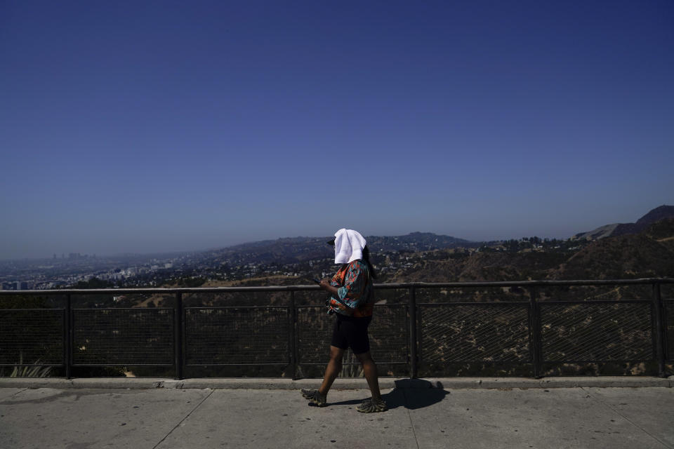 FILE - Tekosha Seals, a tourist visiting from Georgia, walks with a tower over her head at the Griffith Observatory in Los Angeles, Sept. 6, 2022, during a heat wave. Ten years ago scientists warned the world about how climate change would amplify extreme weather disasters. There are now deadly floods, oppressive heat waves, killer storms, devastating droughts and what scientists call unprecedented extremes as predicted in 2012. (AP Photo/Jae C. Hong, File)