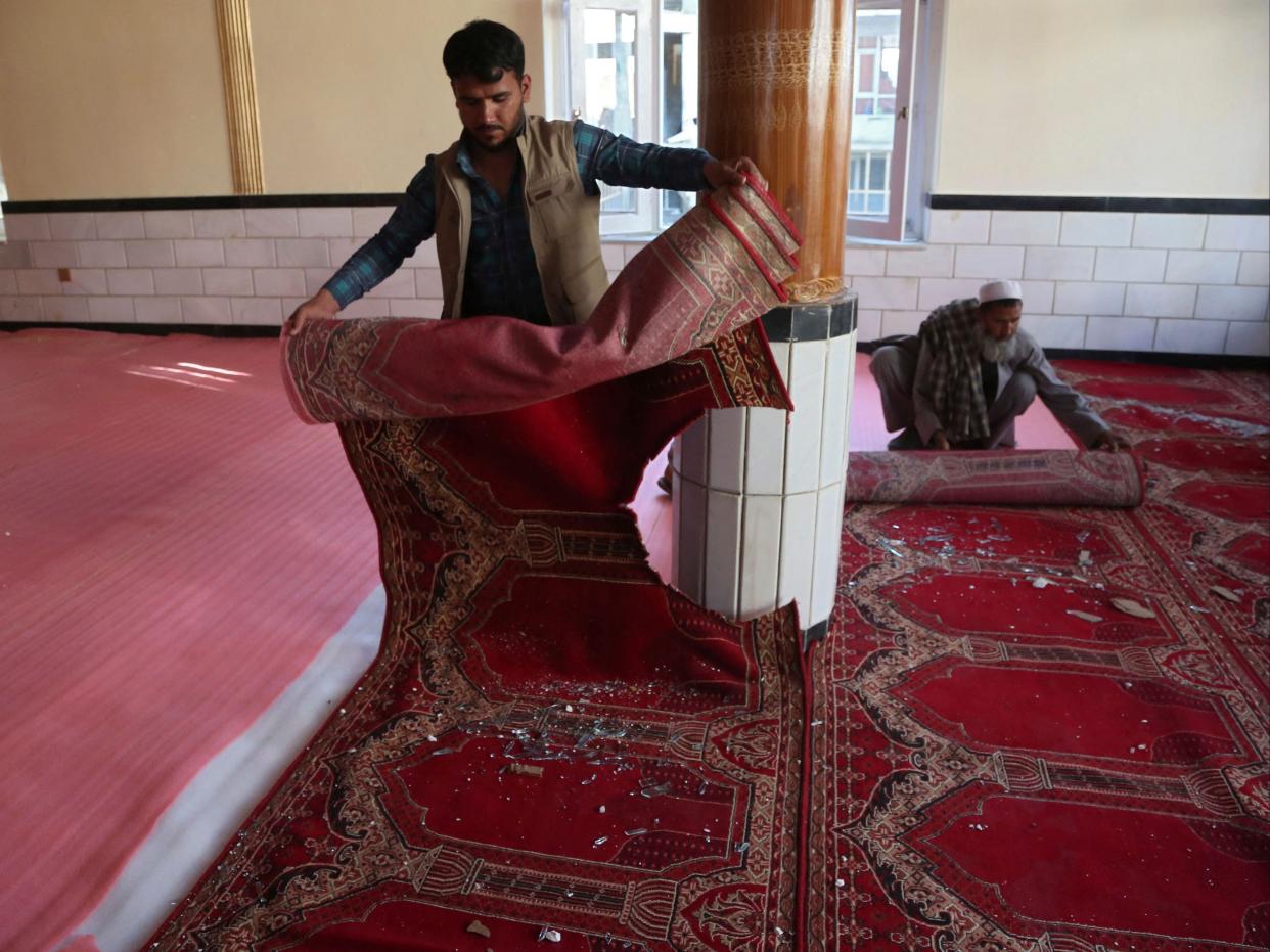 Devotees remove carpets from a mosque after a bomb blast on the outskirts of Kabul on Friday, which killed at least 12 people (AFP via Getty Images)